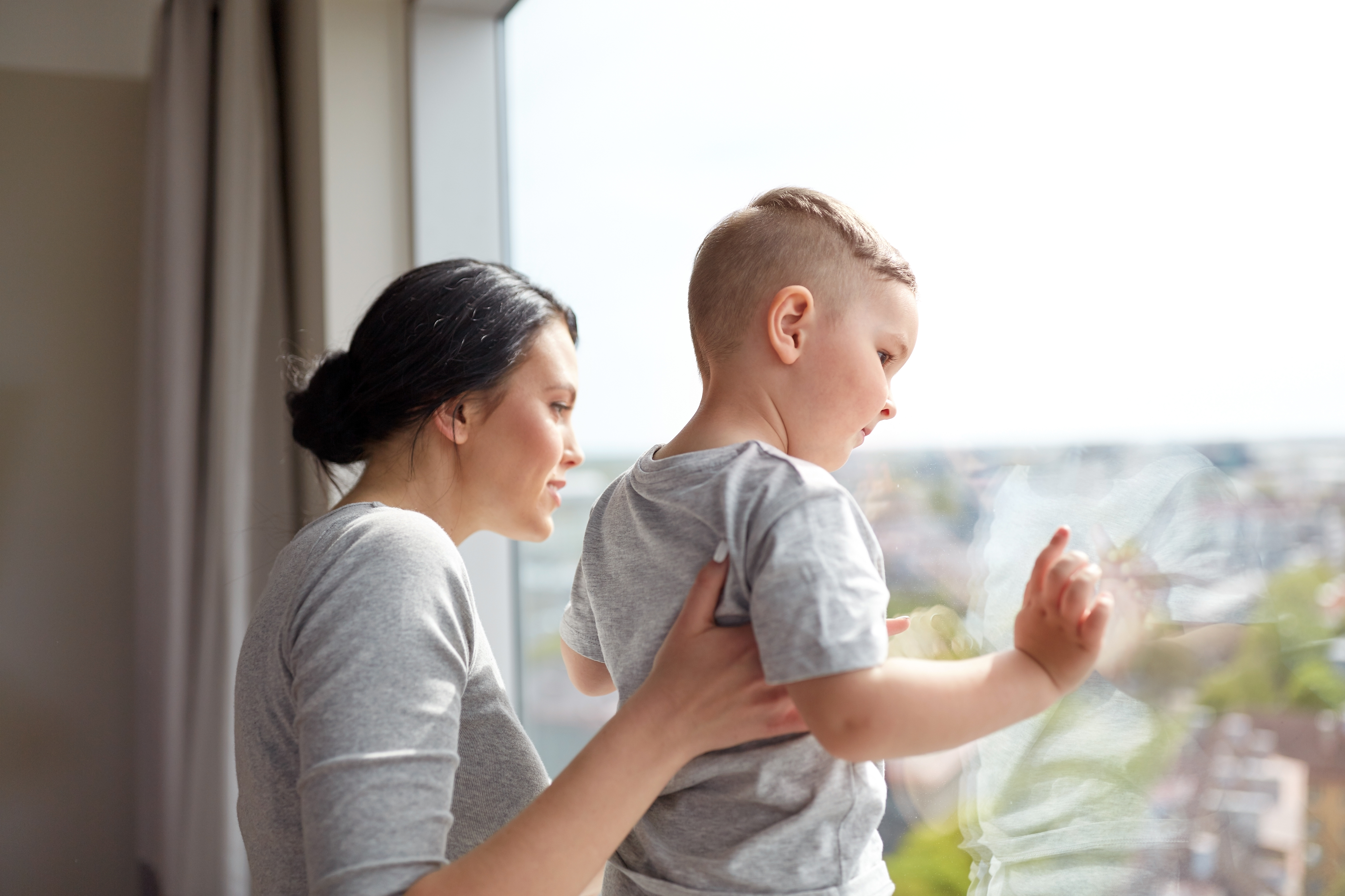 mother and son looking through window at home