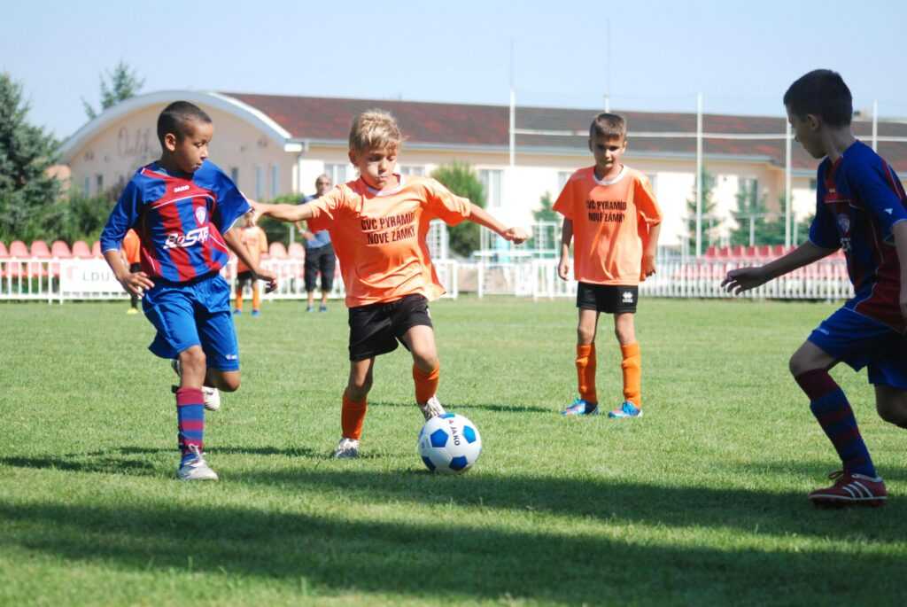 Young boys playing a competitive soccer match outdoors on a sunny day.