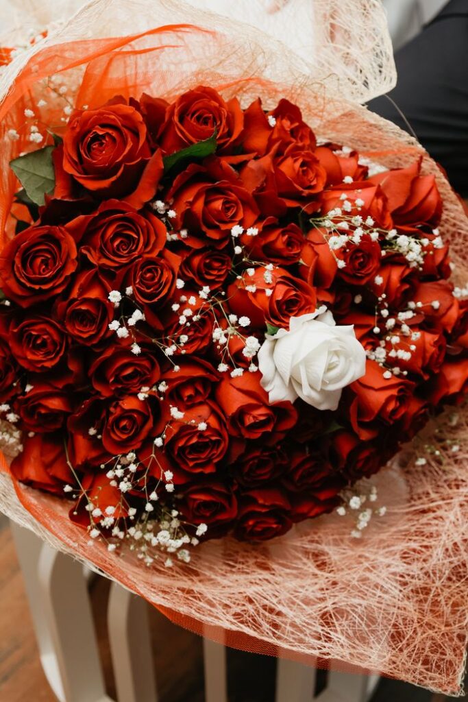 Elegant bouquet of red roses with baby's breath, featuring a single white rose for contrast.